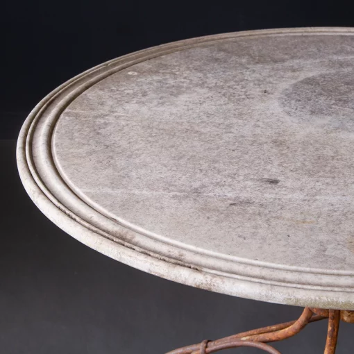 Closeup of left edge of vintage 1920 French round stone outdoor table with iron base